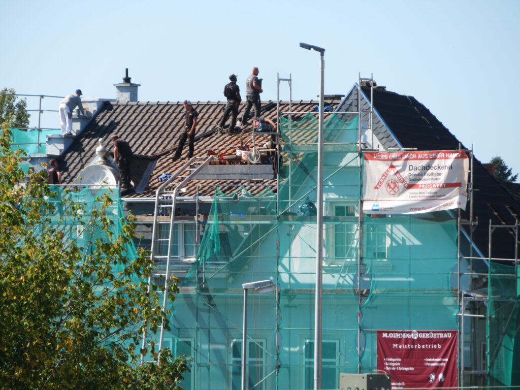 A roofer replacing slates on a pitched UK roof